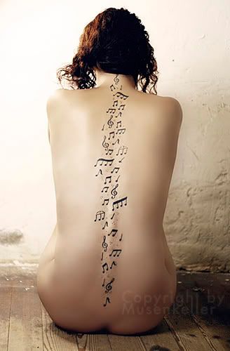 Musical notes trailing down a woman's spine tattoo
